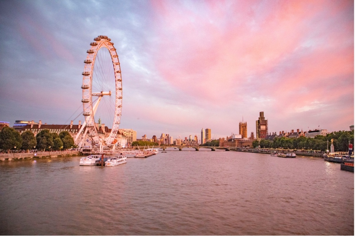 The London Eye stands majestically over the River Thames, bathed in the warm hues of a stunning sunset.