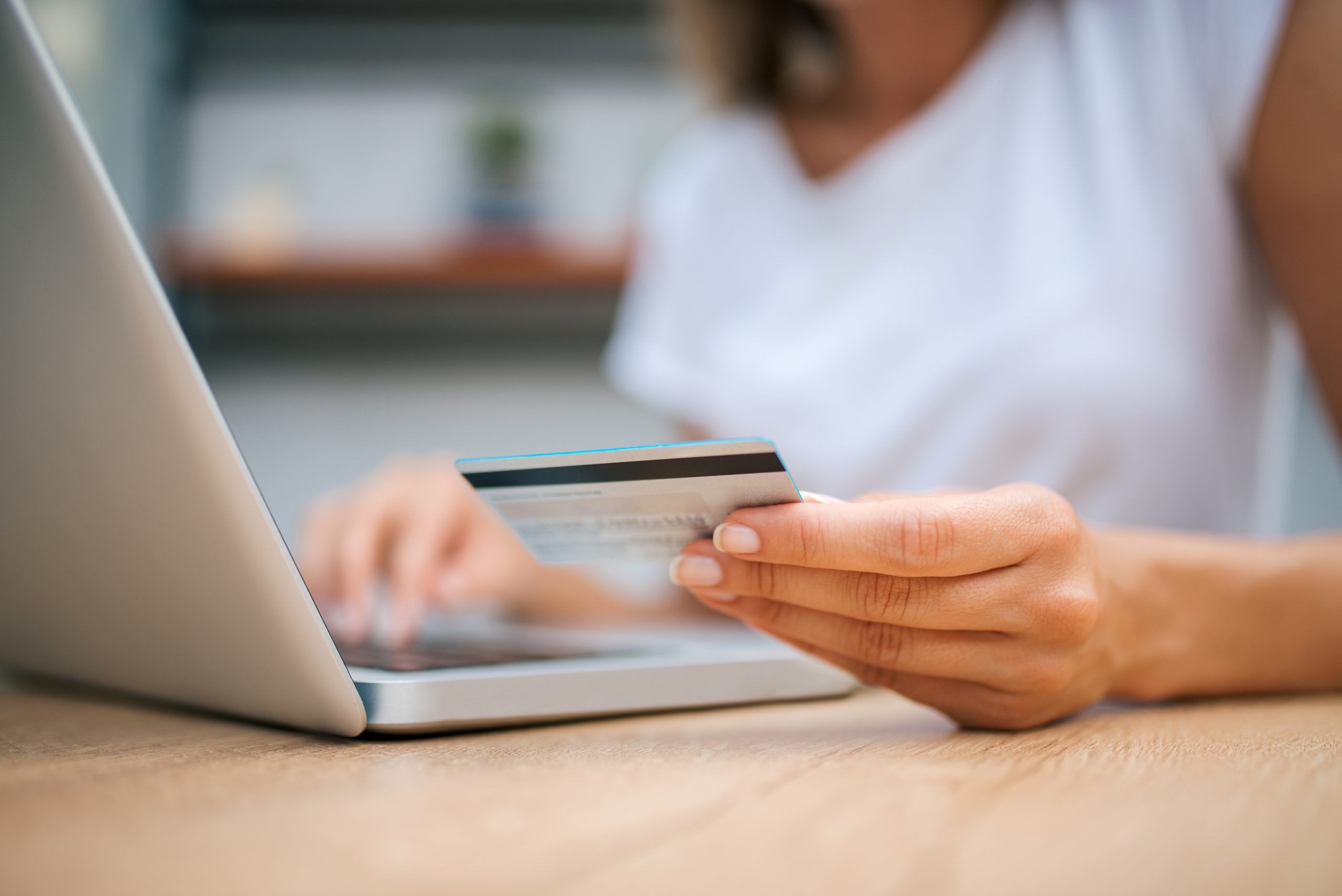 Close-up image of female person using credit card for online shopping.