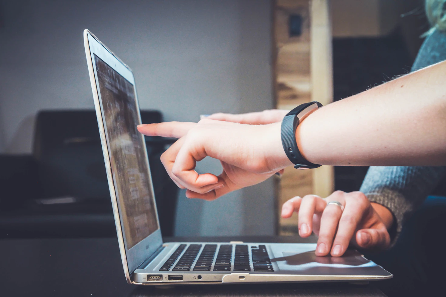 Two persons collaboration on a laptop in an office and one person pointing on laptop screen to present something